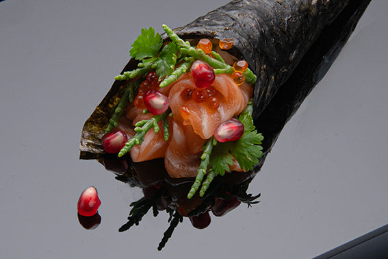 Lachssashimi in Algentüte mit Granatapfelkernen auf Schwarzglas Sushiolatte von Black Glass